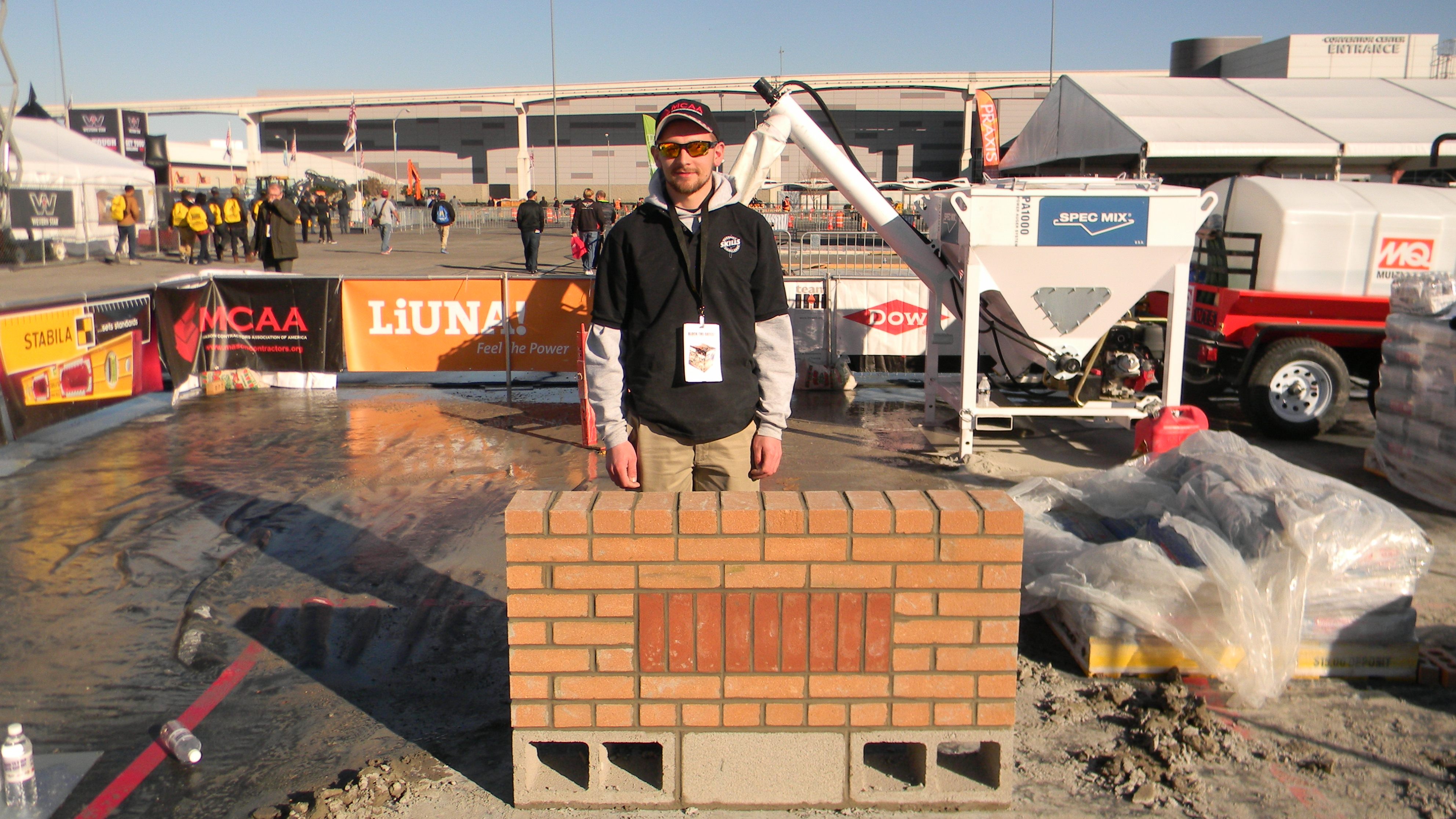 Travis Buda stands with the short brick wall he built during the competition.